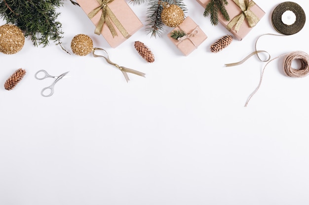 Weihnachtsbälle, Tannenzweige, Geschenk, Band, Seil und Scheren auf einer weißen Tabelle, Draufsicht