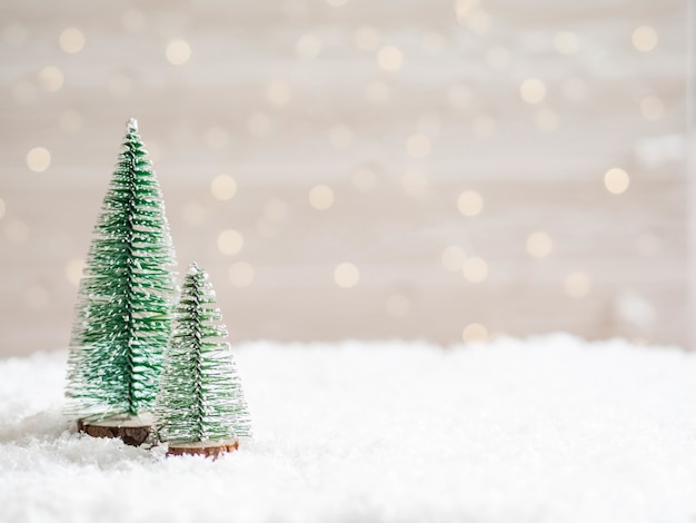 Foto weihnachtsbäume im vordergrund im kunstschnee mit einer leuchtenden girlande. speicherplatz kopieren.