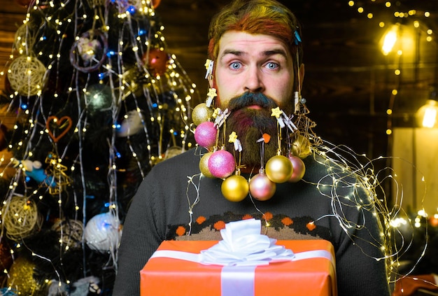 Weihnachtsbartdekorationen überraschten bärtigen Mann mit Geschenkbox Neujahrsferien
