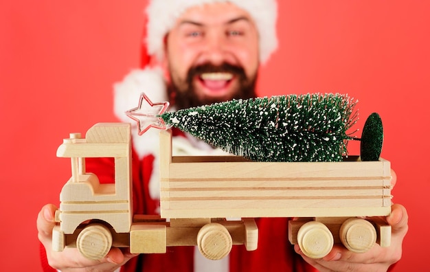 Weihnachtsbaum auf hölzernem Spielzeug-LKW-Auto Weihnachtsmann mit Tannenbaum-Lieferservice frohes neues Jahr