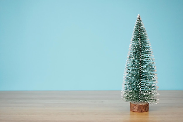 Weihnachtsbaum auf Holztisch mit blauem Wandhintergrund