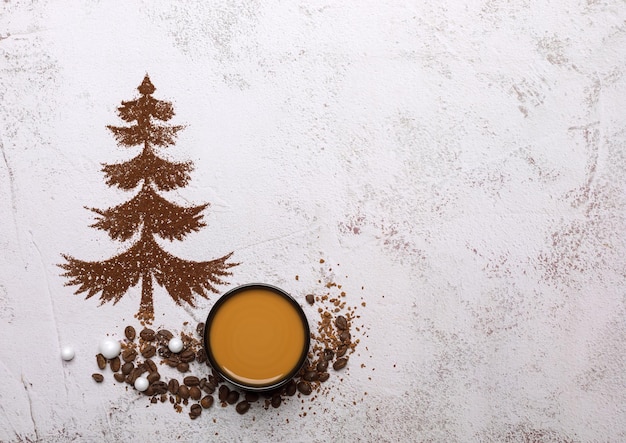 Weihnachtsbaum aus Boden und Kaffeekörnern auf einem Leuchttisch mit einer Tasse Kaffee