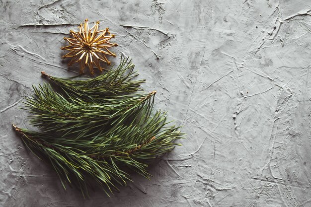 Weihnachtsbaum aus Kiefernblättern und Strohspielzeug. auf grauem Betongrund.