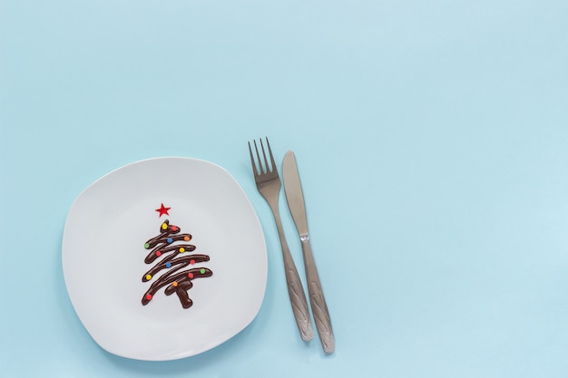 Weihnachtsbaum der süßen Schokolade auf Platte und Tischbesteck