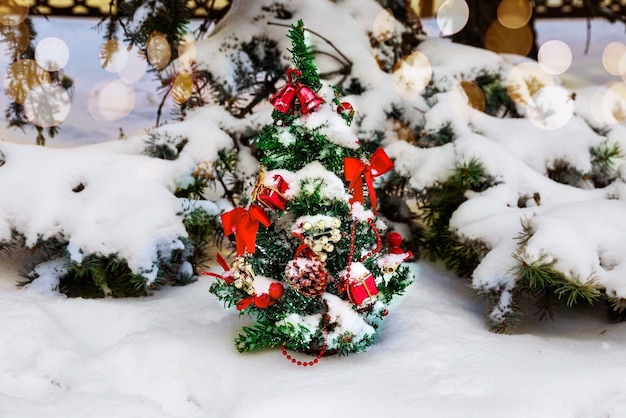 Weihnachtsbaum geschmückt mit Girlanden und Spielzeug an der frischen Luft im Park im Winter unter Schnee