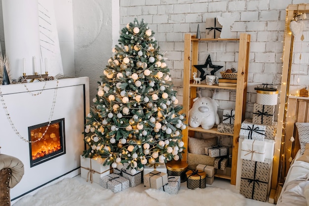 Weihnachtsbaum geschmückt mit weißem Spielzeug zu Hause mit einem Kamin mit vielen verpackten Geschenkboxen