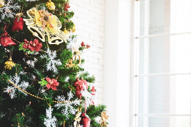 Weihnachtsbaum im Grün mit rotem Dekor im Raum.