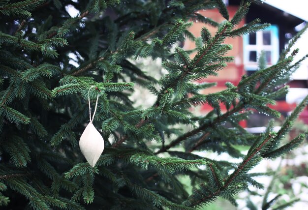 Weihnachtsbaum in der Nähe des Hauses mit handgeschöpftem Papierspielzeug