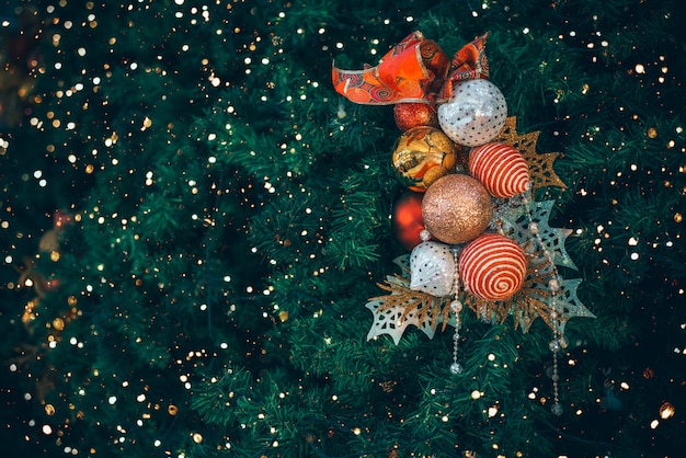 Weihnachtsbaum mit Balldekoration mit Licht auf Baum. Weihnachts- und Neujahrsfeiertagshintergrund. Vintage Farbton. Nahansicht .