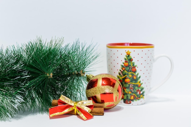 Weihnachtsbaum mit Becher, Zimt und roter Kugel isoliert auf weißem Hintergrund