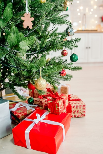 Foto weihnachtsbaum mit bunten kugeln und geschenkboxen auf weißem küchenhintergrund