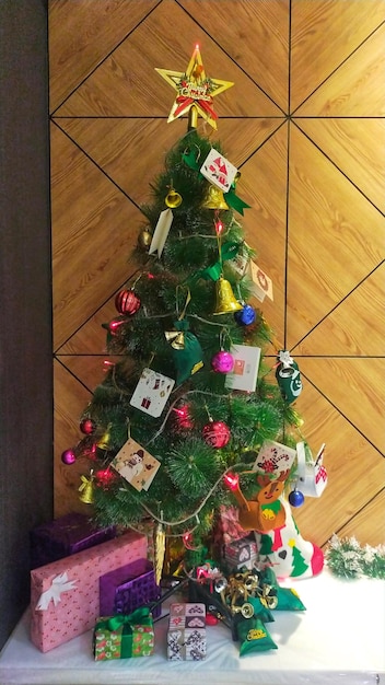 Weihnachtsbaum mit Dekoration und Geschenkbox in der Ecke des Zimmers