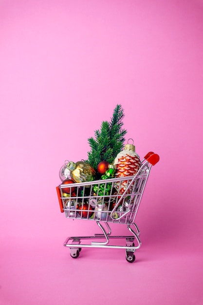 Weihnachtsbaum mit Dekorationen in einem Supermarktwarenkorb. Weihnachtseinkauf und Verkaufskonzept