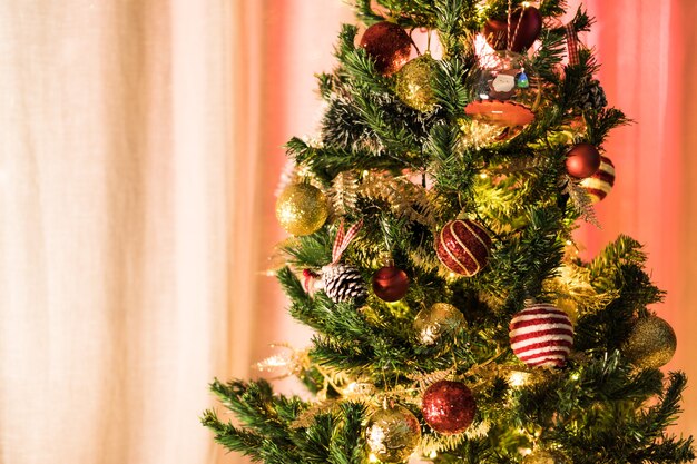 Weihnachtsbaum mit Ornamenten montiert. Rote, silberne und goldene Kugeln, Geschenkboxen, Lichter, Weihnachtsmann und andere. Selektiver Fokus.