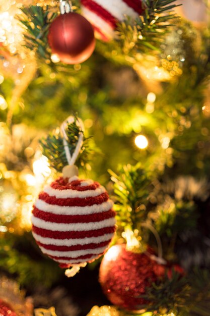 Weihnachtsbaum mit Ornamenten montiert. Rote, silberne und goldene Kugeln, Geschenkboxen, Lichter, Weihnachtsmann und andere. Selektiver Fokus.