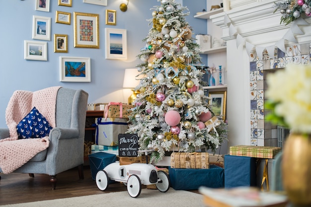 Weihnachtsbaum mit Spielwaren, Girlanden, Kästen mit Geschenken in einem gemütlichen Hauptinnenraum.