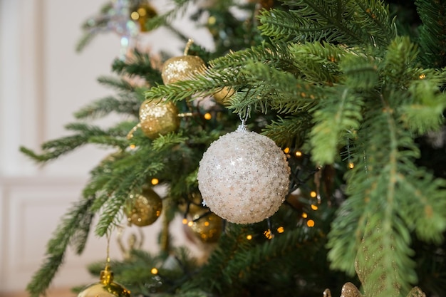 Weihnachtsbaum mit Vintage-Eichel und Kugeln mit goldenen Lichtern aus nächster Nähe Modern geschmückte Weihnachtsbaumzweige mit stilvollen Ornamenten im festlichen Raum Winterferien stimmungsvolle Zeit