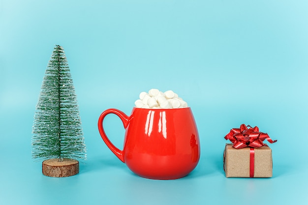 Weihnachtsbaum, Schale des Eibisches und Geschenkbox auf blauer Wand. Frohe Weihnachten oder ein glückliches neues Jahr-Konzept.