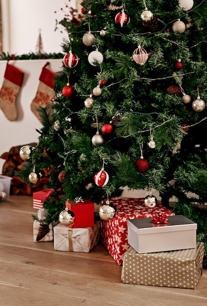 Weihnachtsbaum und Geschenk auf dem Boden eines Wohnzimmers zur Feier oder Vorbereitung auf die festliche Jahreszeit Morgengeschenk und Tradition mit einem Weihnachtsbaum in einem Haus für Weihnachtsferien