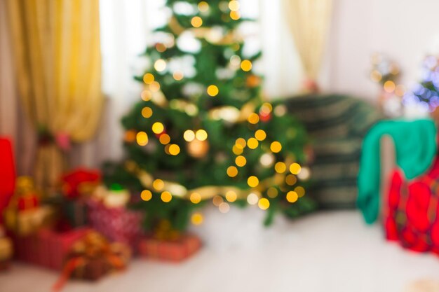 Weihnachtsbaum und Geschenke im Zimmer. Verschwommener defokussierter Lichthintergrund für Design, Urlaubskonzept