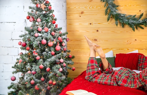 Weihnachtsbaum und Mädchen im Pyjama. Selektiver Fokus. Urlaub.