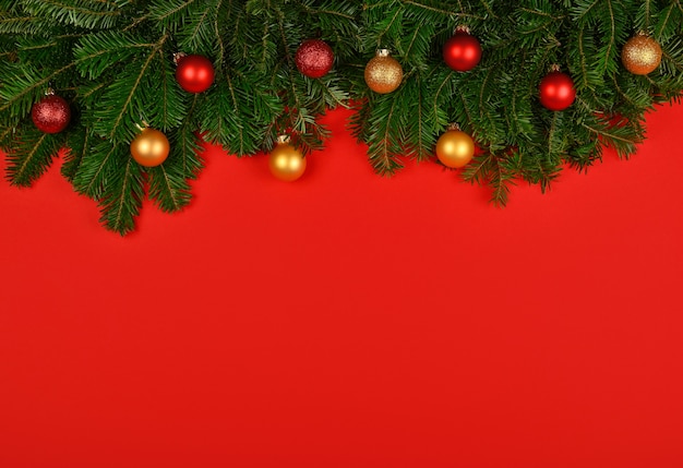 Weihnachtsbaum verziert mit bunten Kugeln über rotem Hintergrund