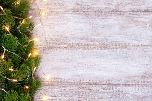 Weihnachtsbaum verziert mit einer gelben Girlande auf einem hölzernen Hintergrund