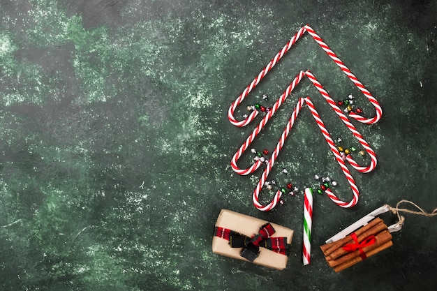 Weihnachtsbaum von den Zuckerstangen und vom Kasten mit Geschenk auf einer grünen Oberfläche