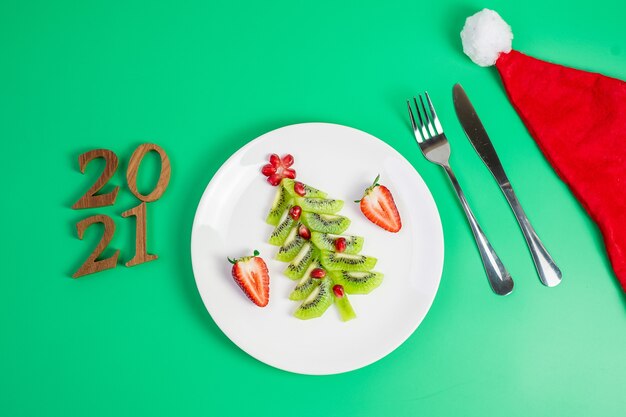 Weihnachtsbaum von Kiwi und Granatapfel mit Gabel und Messer