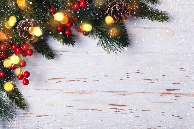 Weihnachtsbaumast mit Dekorationen auf weißem hölzernem Hintergrund.