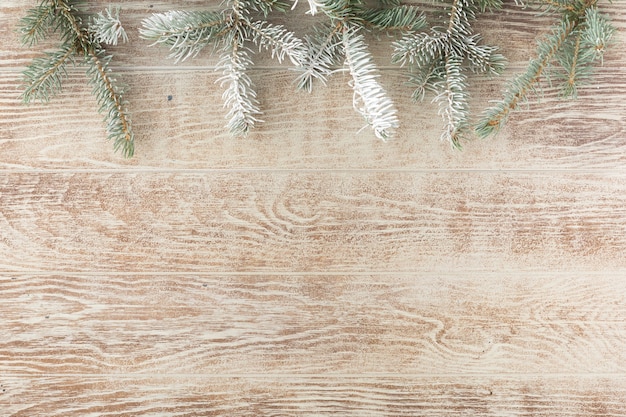 Weihnachtsbaumast mit Tannenzapfen auf rustikalem Holztisch. Winterhintergrund mit Kopienraum. Ansicht von oben. Flach legen