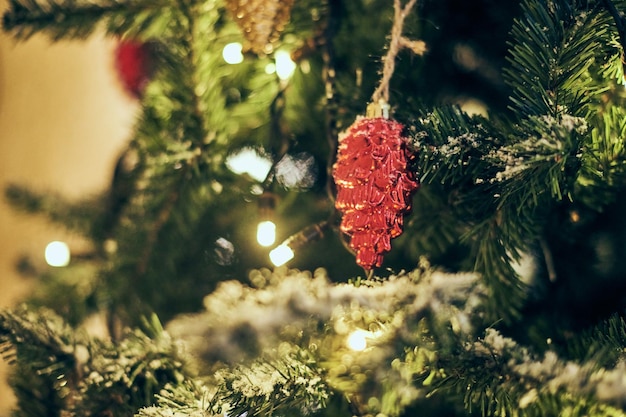 Weihnachtsbaumbirnen mit gelben Girlanden bedeckten schneebedeckten Weihnachtsbaum im Freien mit dekorativen roten Birnen