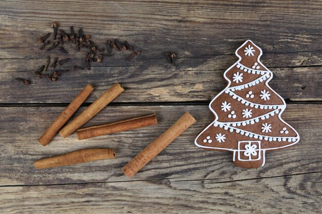 Foto weihnachtsbaumkekse und zimtstäbchen auf hölzernem hintergrund