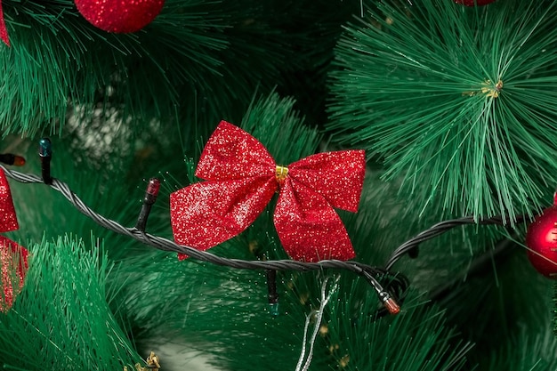 Weihnachtsbaumnahaufnahme verziert mit einer roten Schleife. Urlaubskonzept.