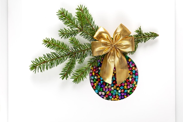 Weihnachtsbaumspielzeug aus farbigen Schlittenglocken mit goldener Schleife auf weißem Hintergrund