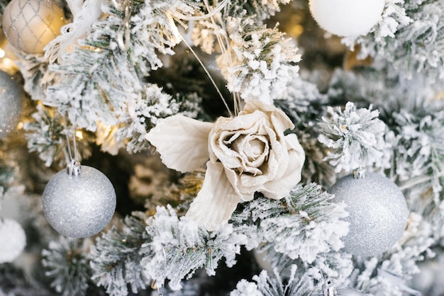 Weihnachtsbaumspielzeug in Form einer Rose hängt an einem silbernen Weihnachtsbaum Weihnachtshintergrund