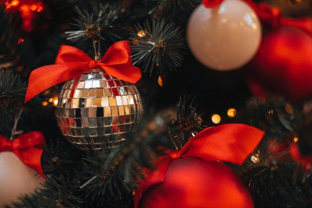 Weihnachtsbaumzweige mit Weihnachtskugel und roten seidigen Bögen dekoriert Wintersaison des neuen Jahres