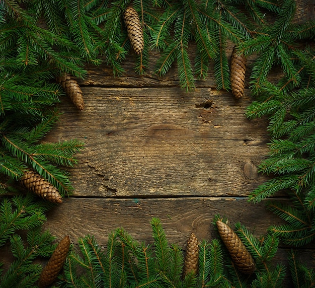 Weihnachtsbaumzweige mit Zapfen auf Holzstruktur bereit für Ihr Design