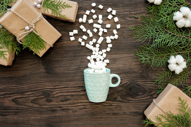 Weihnachtsbecher, Marshmallow und Geschenkboxen auf dunklem Holzbrett, Draufsicht