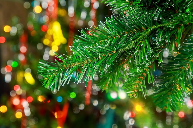 Weihnachtsbeleuchtung, die in einem Baumast auf dem Hintergrund des Weihnachtsbaums hängt