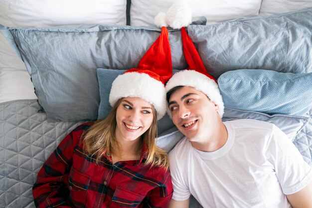 Weihnachtsbeziehungen und Wohnkonzept Junges heterosexuelles Paar liegt in Weihnachtsmützen auf dem Bett