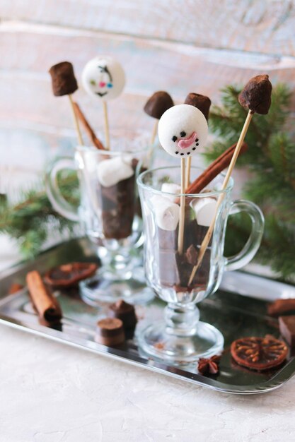 Weihnachtsbonbons schwarze Schokolade und Baiser auf Stäbchen in Glasbechern Gewürze Fichtenzweige