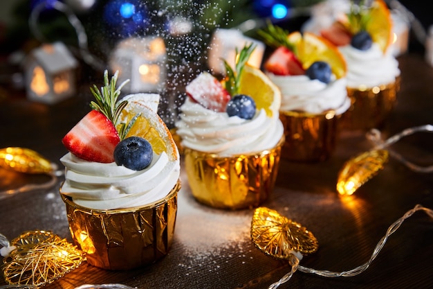 Weihnachtscupcakes dekoriert mit frischen Blaubeeren und Erdbeeren