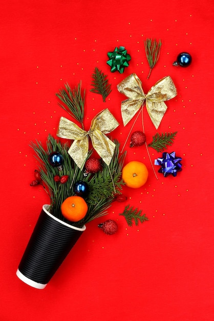 Weihnachtsdekor, das aus einem Pappbecher auf rotem Hintergrund strömt