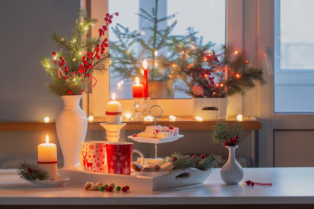 Weihnachtsdekor und rote Tassen mit heißem Getränk in der Küche