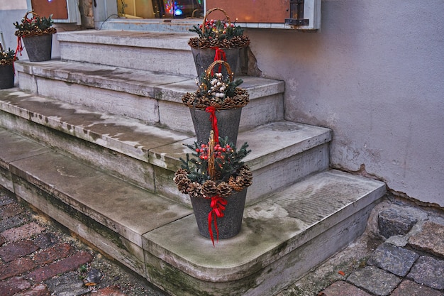 Weihnachtsdekoration auf der Treppe des Cafés. Blecheimer mit Tannenzapfen und Zierbändern. Straßenweihnachtsdekoration im Urlaub