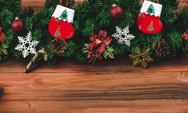 Weihnachtsdekoration auf Holzhintergrund mit Kopienraum, Kiefernzweigen, Weihnachtssocken und verschiedenen Arten von Ornamenten, die von hoch über dem Blickwinkel aufgenommen wurden.