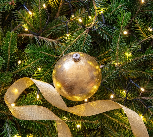 Weihnachtsdekoration auf Tanne und Lichter Hintergrund kopieren Raum Goldene Weihnachtskugel und Farbband