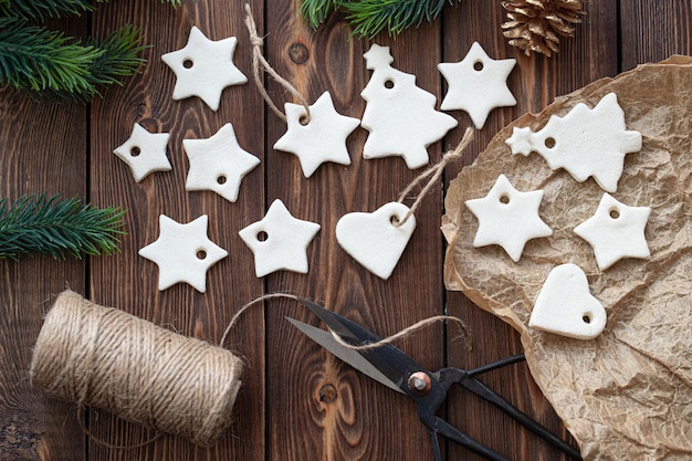 Foto weihnachtsdekoration aus gesalzenem teig in form von sternen und herzen liegen auf einem holztisch.