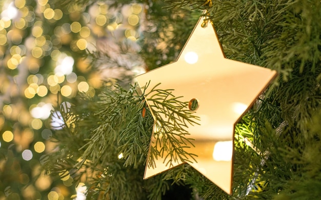 Weihnachtsdekoration eines goldenen Sterns, der am Baum hängt